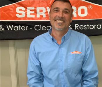 SERVPRO employee in blue shirt in front of SERVPRO sign